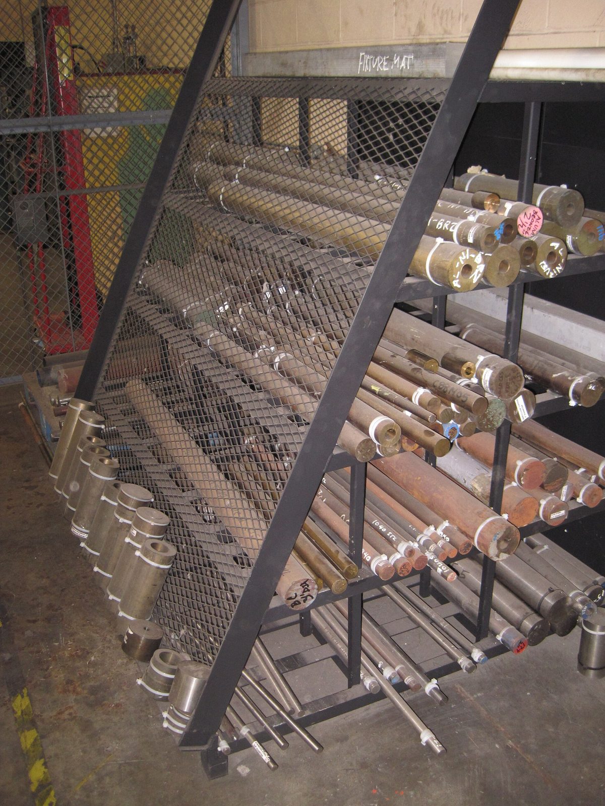 Illustrative raw metal sheet and tube stock on racks in a fabrication shop